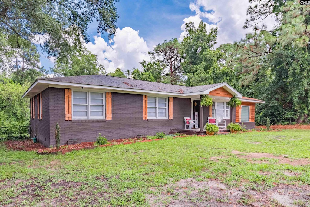 ranch-style house with a front yard and covered porch