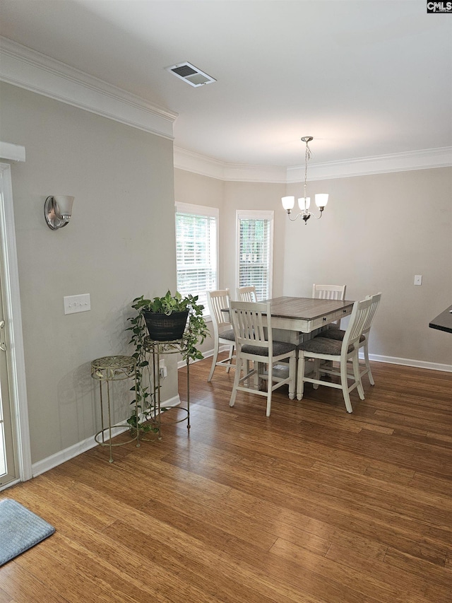 unfurnished dining area with a notable chandelier, visible vents, ornamental molding, wood finished floors, and baseboards