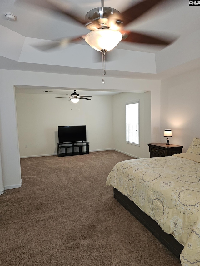 carpeted bedroom with baseboards, a raised ceiling, and a ceiling fan