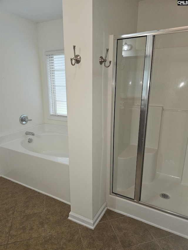 bathroom with a stall shower, baseboards, a bath, and tile patterned floors