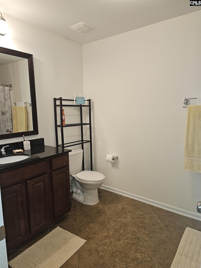 bathroom featuring toilet, vanity, and baseboards