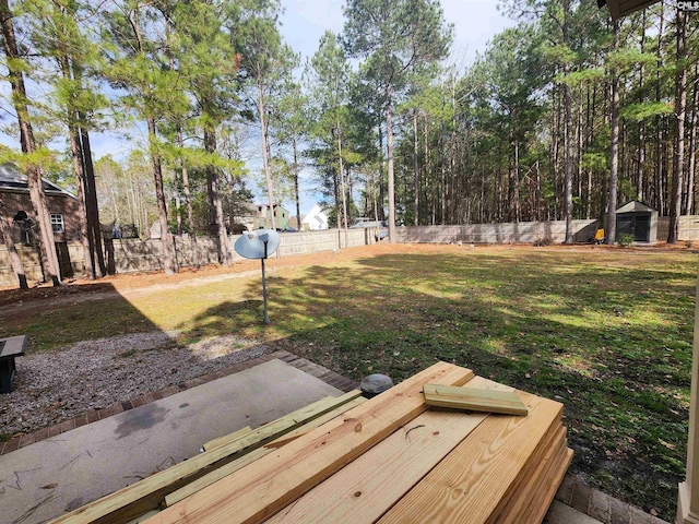 view of yard featuring a shed, a fenced backyard, and an outbuilding