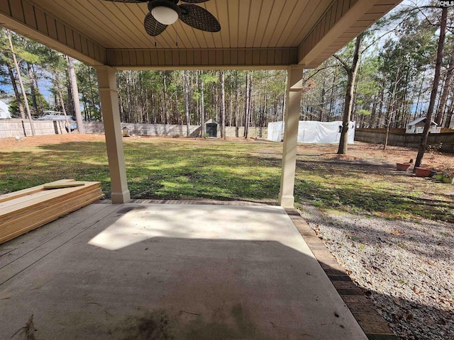 view of patio / terrace with a fenced backyard, ceiling fan, an outdoor structure, and a storage shed