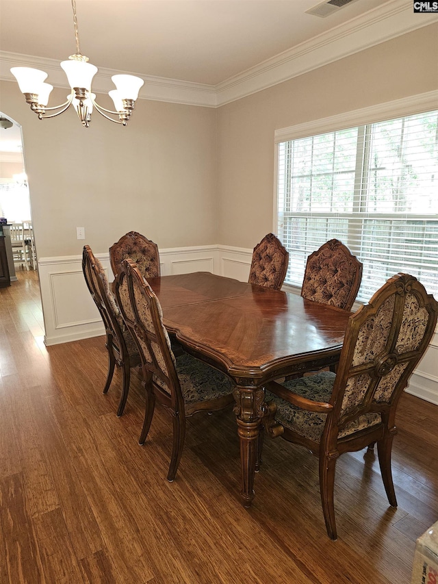 dining room with ornamental molding, a chandelier, wood finished floors, and wainscoting