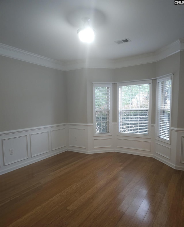 unfurnished room featuring dark wood-style flooring, visible vents, and crown molding