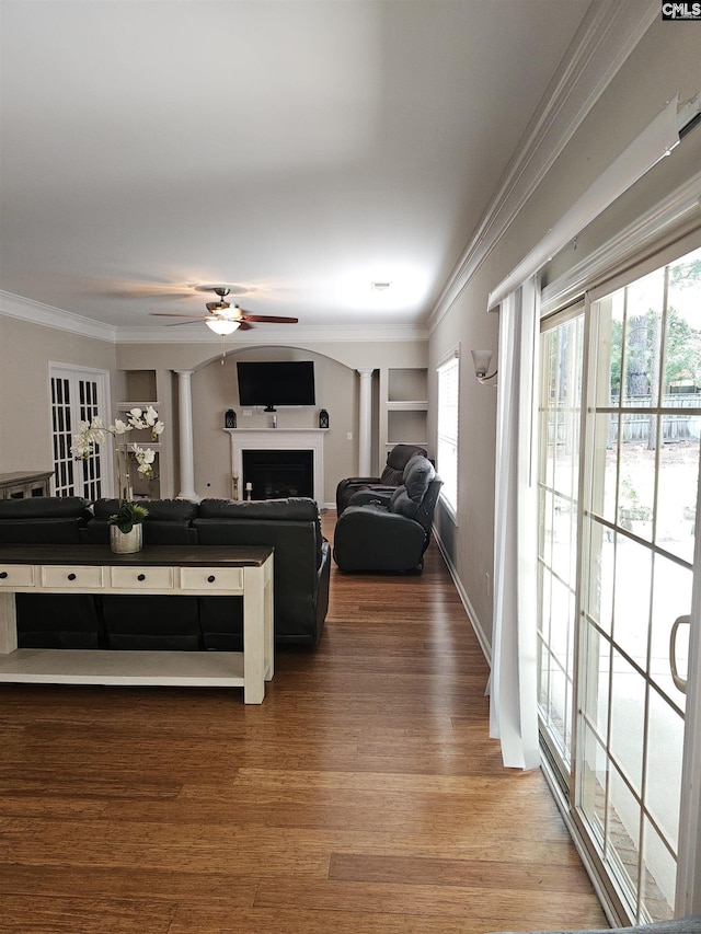 living room with ceiling fan, a fireplace, crown molding, and wood finished floors