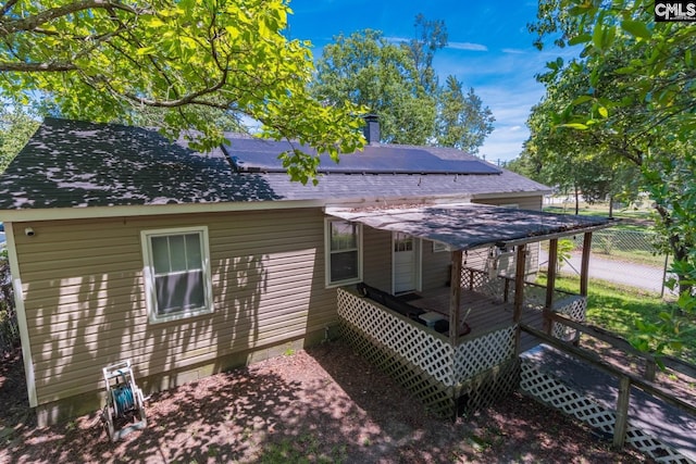 rear view of property featuring a deck and solar panels