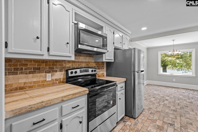 kitchen featuring decorative light fixtures, ornamental molding, stainless steel appliances, decorative backsplash, and white cabinets