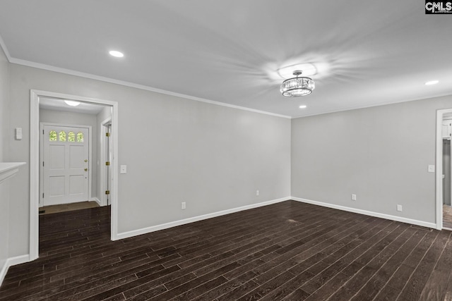 empty room with dark wood-type flooring, ornamental molding, and an inviting chandelier