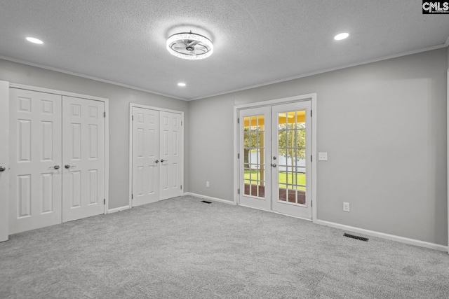 unfurnished bedroom featuring carpet flooring, ornamental molding, access to outside, multiple closets, and french doors