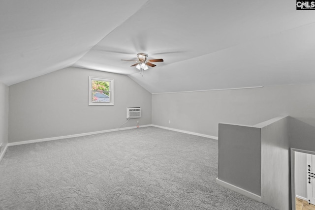 additional living space with light colored carpet, vaulted ceiling, a wall unit AC, and ceiling fan