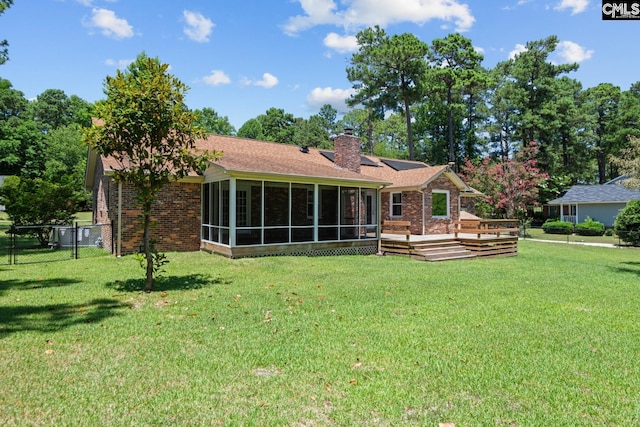 rear view of property with a wooden deck, a sunroom, and a lawn