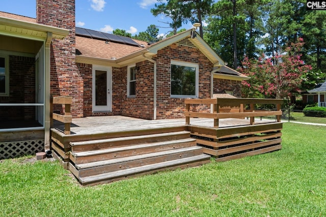 rear view of house featuring a wooden deck, a yard, and solar panels