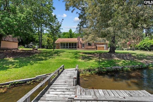 view of dock with a water view and a lawn