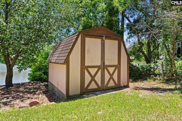 view of outbuilding featuring a water view and a lawn