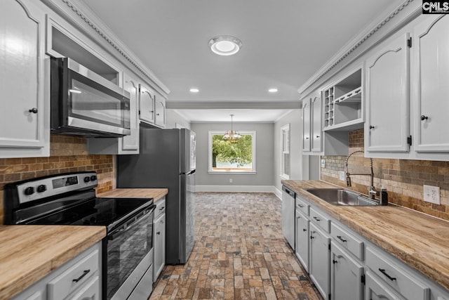 kitchen with pendant lighting, sink, crown molding, appliances with stainless steel finishes, and white cabinets