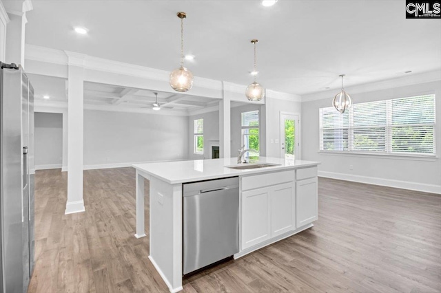 kitchen with light wood finished floors, open floor plan, light countertops, appliances with stainless steel finishes, and a sink