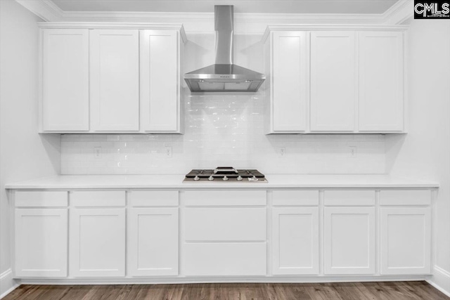 kitchen with tasteful backsplash, white cabinetry, light countertops, and wall chimney range hood