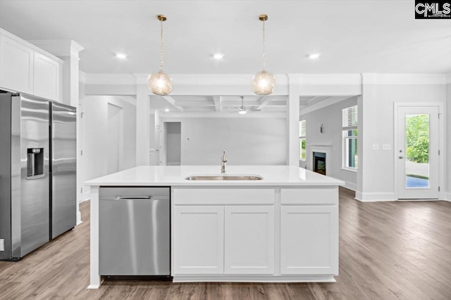 kitchen featuring a kitchen island with sink, a sink, white cabinets, appliances with stainless steel finishes, and open floor plan