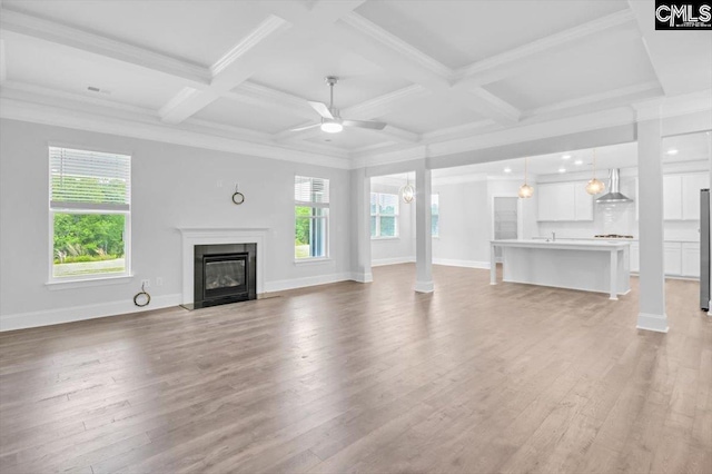 unfurnished living room with baseboards, a fireplace with flush hearth, ceiling fan, and light wood finished floors