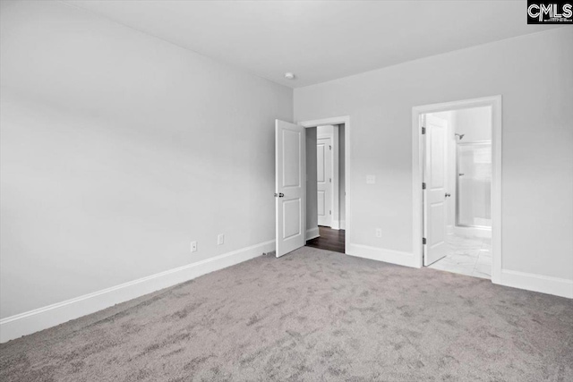 unfurnished bedroom featuring ensuite bath, carpet flooring, and baseboards