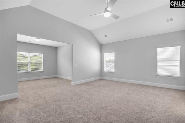 spare room featuring a wealth of natural light, light carpet, ceiling fan, and vaulted ceiling