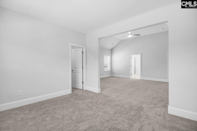 empty room featuring carpet flooring, a ceiling fan, baseboards, and vaulted ceiling