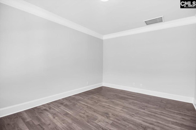 empty room featuring dark wood-style floors, visible vents, crown molding, and baseboards