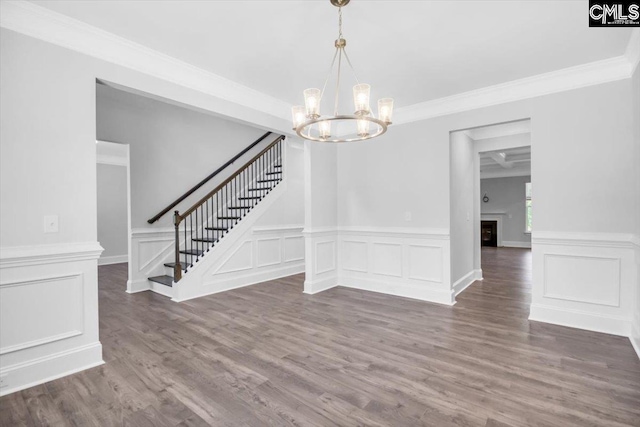 unfurnished dining area with crown molding, stairway, a notable chandelier, and wood finished floors