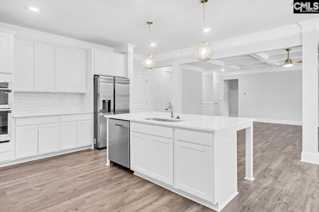 kitchen featuring a sink, light countertops, light wood-style floors, appliances with stainless steel finishes, and tasteful backsplash