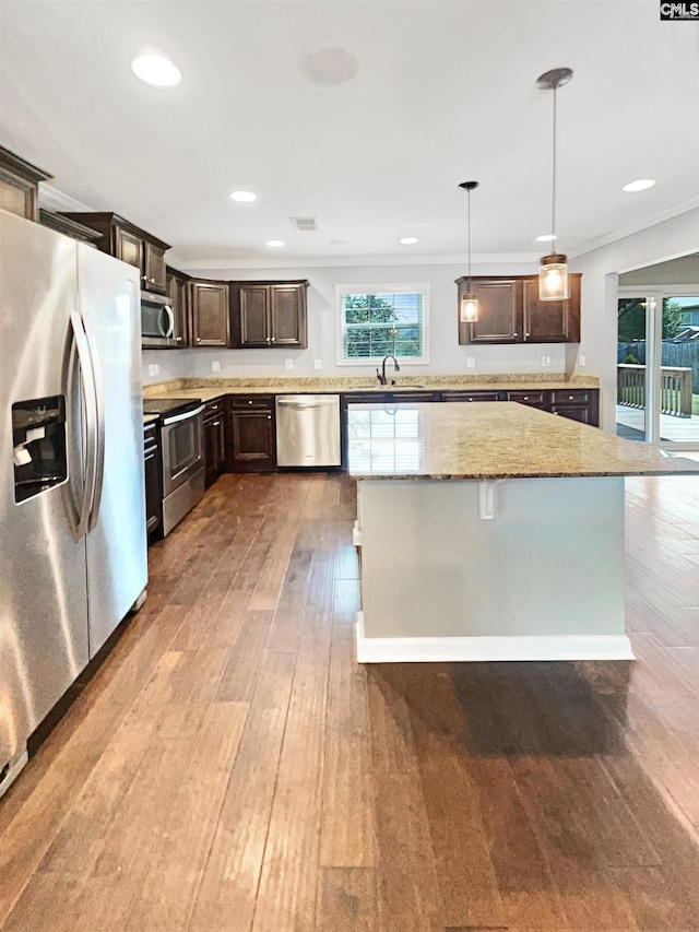 kitchen featuring light stone countertops, dark brown cabinets, hanging light fixtures, and stainless steel appliances