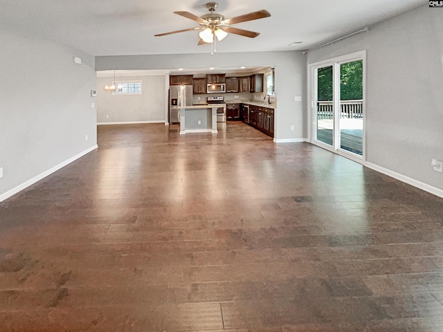 unfurnished living room featuring sink and ceiling fan with notable chandelier