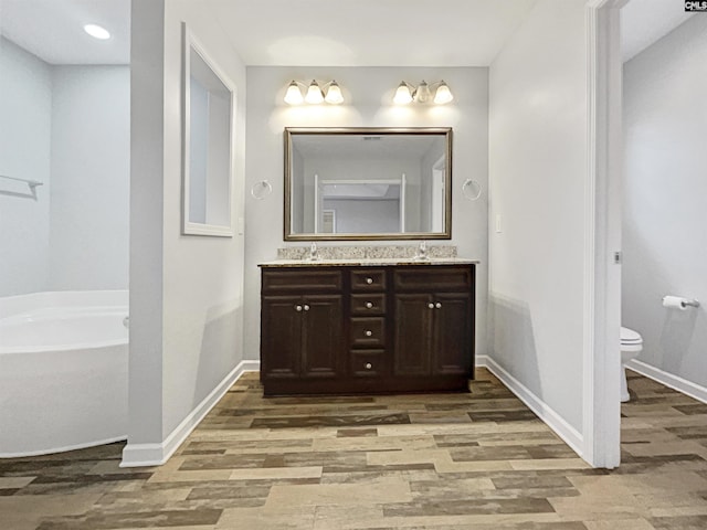 bathroom featuring toilet, hardwood / wood-style flooring, a tub, and vanity