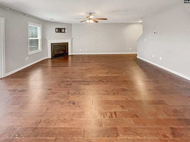 unfurnished living room featuring ceiling fan and dark hardwood / wood-style flooring