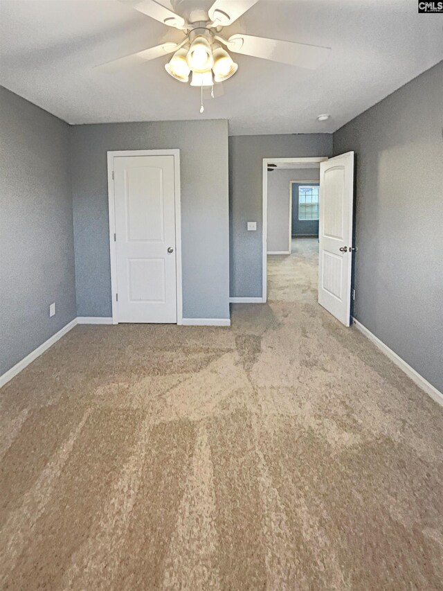 spare room with ceiling fan and light carpet