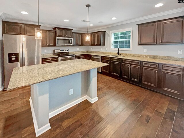 kitchen with pendant lighting, ornamental molding, stainless steel appliances, and a kitchen island