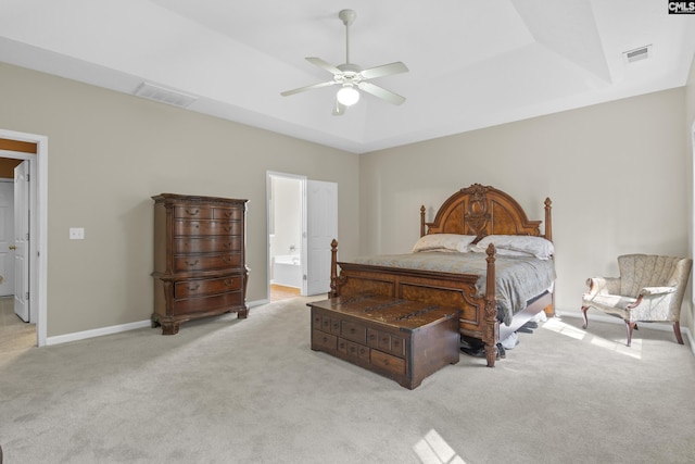 carpeted bedroom with ensuite bathroom, a raised ceiling, and ceiling fan