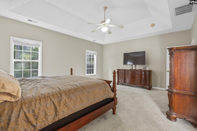 bedroom featuring ceiling fan, a tray ceiling, and light colored carpet