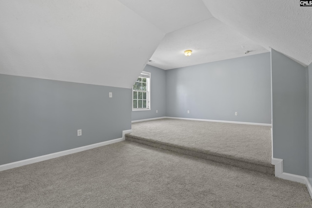 bonus room with lofted ceiling, a textured ceiling, and carpet