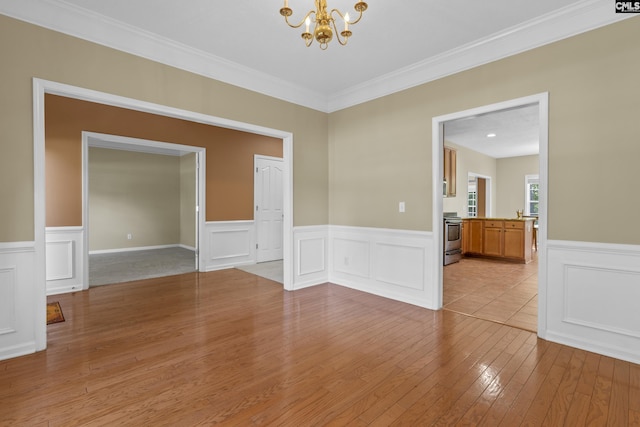 empty room with a chandelier, light hardwood / wood-style floors, and ornamental molding