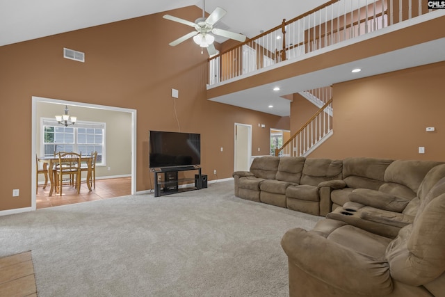 carpeted living room featuring ceiling fan with notable chandelier and high vaulted ceiling