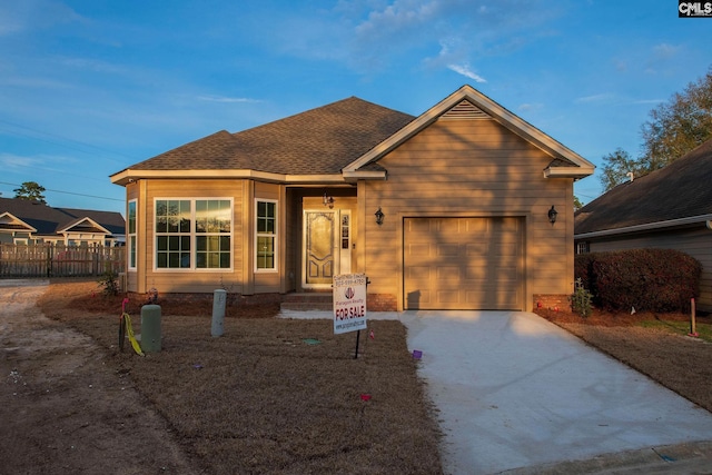 view of front of house featuring a garage, concrete driveway, a shingled roof, and fence