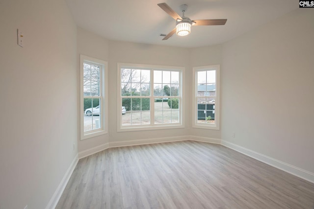 unfurnished room featuring a ceiling fan, light wood finished floors, and baseboards