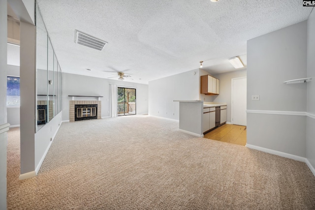 unfurnished living room with ceiling fan, sink, light colored carpet, and a textured ceiling