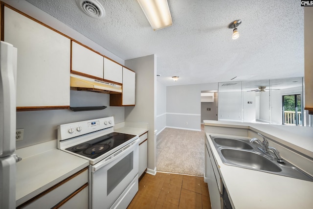 kitchen with kitchen peninsula, white cabinetry, light carpet, and white appliances