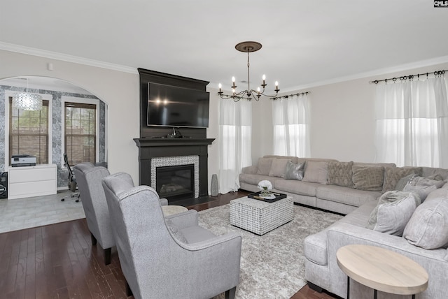 living room with a notable chandelier, a fireplace, ornamental molding, and dark wood-style flooring