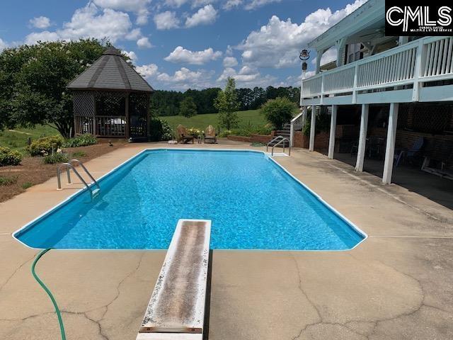 view of swimming pool featuring a deck, a patio, and a gazebo