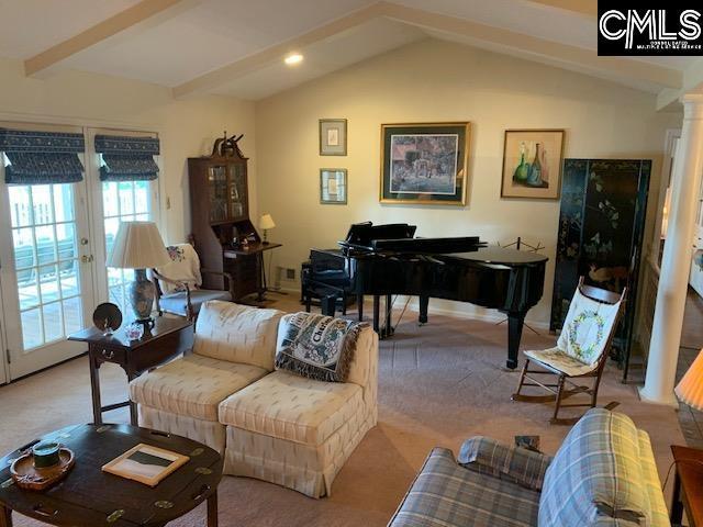 living area with french doors, ornate columns, vaulted ceiling with beams, and light colored carpet