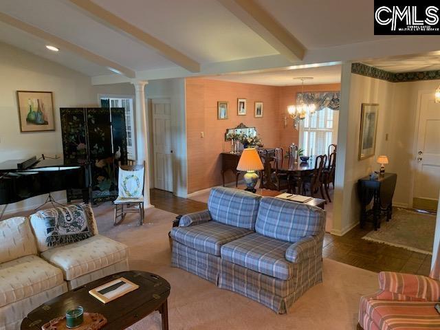 living room with decorative columns, vaulted ceiling with beams, and a notable chandelier