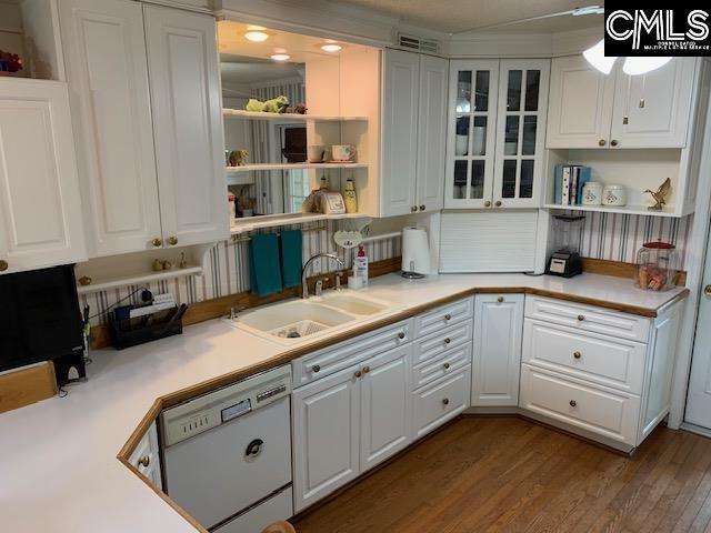 kitchen with white cabinetry, white dishwasher, hardwood / wood-style flooring, and sink